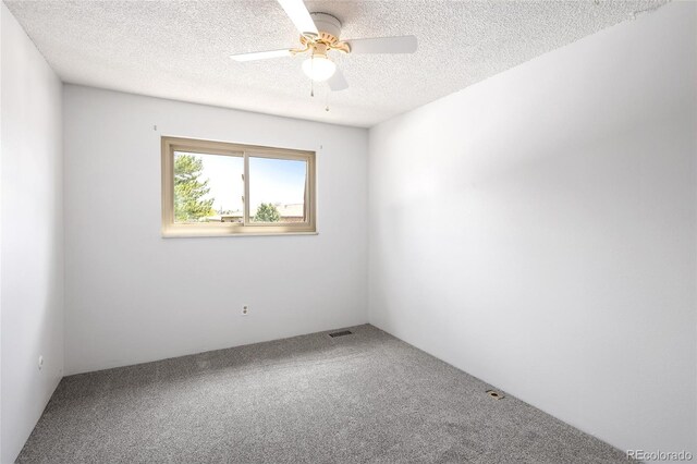 empty room with ceiling fan, a textured ceiling, carpet floors, and visible vents
