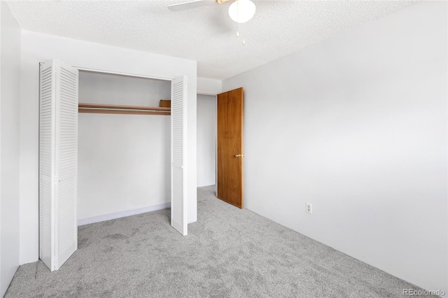 unfurnished bedroom featuring a textured ceiling, carpet floors, a closet, and a ceiling fan