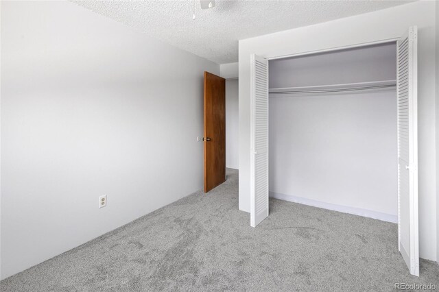 unfurnished bedroom with carpet, a textured ceiling, and a closet