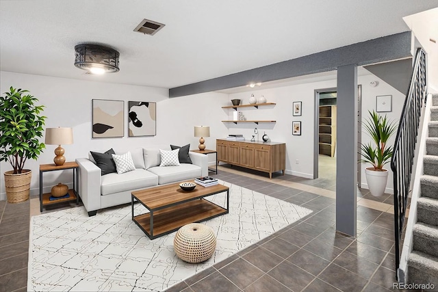 living room featuring baseboards, stairs, and visible vents