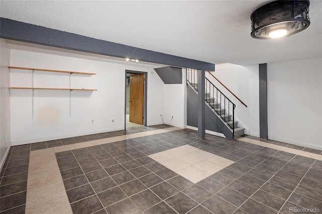 finished below grade area featuring tile patterned floors, baseboards, and stairs