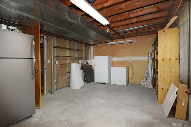 unfinished basement with freestanding refrigerator and refrigerator