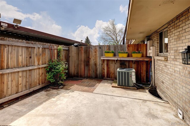 view of patio with central air condition unit and fence