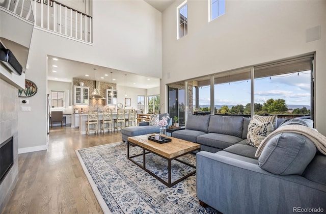 10401 Maplebrook Way, Highlands Ranch, CO 80126 - living area featuring wood finished floors, a towering ceiling, and a tiled fireplace