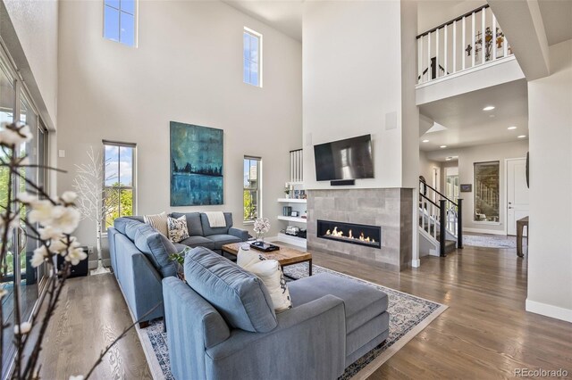 10401 Maplebrook Way, Highlands Ranch, CO 80126 - living room featuring a towering ceiling, a tile fireplace, wood finished floors, healthy amount of natural light, and recessed lighting