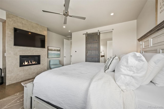 10401 Maplebrook Way, Highlands Ranch, CO 80126 - bedroom featuring a tiled fireplace, dark wood finished floors, recessed lighting, a barn door, and a ceiling fan
