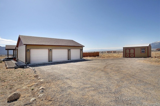 detached garage featuring a storage shed and fence