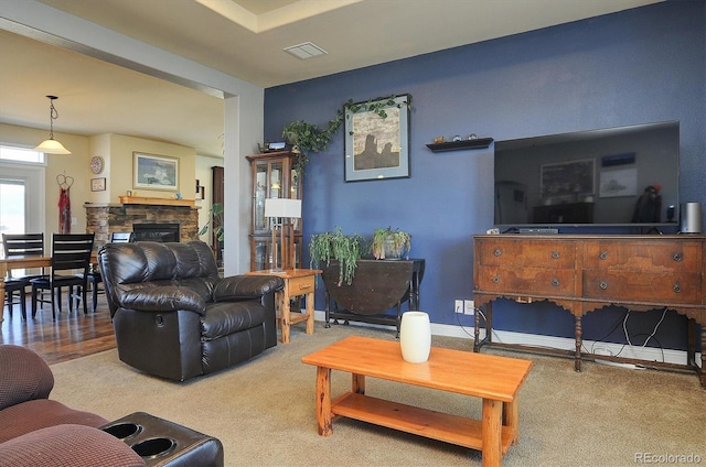 living area featuring visible vents, a stone fireplace, and carpet