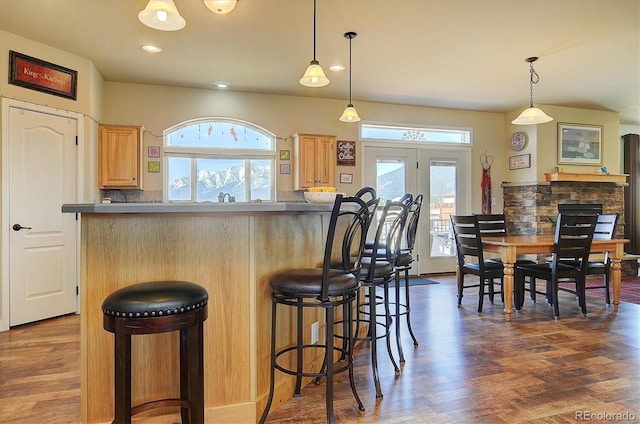 kitchen featuring light brown cabinets, dark wood-style flooring, a kitchen bar, recessed lighting, and pendant lighting