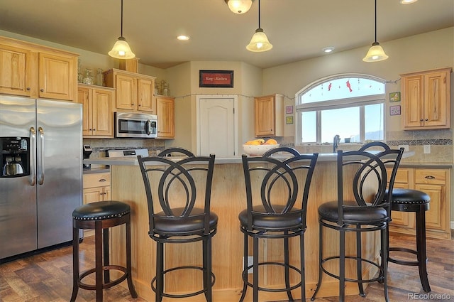 kitchen featuring stainless steel appliances, tasteful backsplash, a breakfast bar area, and light brown cabinetry
