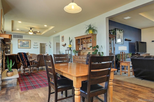 dining area with visible vents, a raised ceiling, ceiling fan, recessed lighting, and wood finished floors