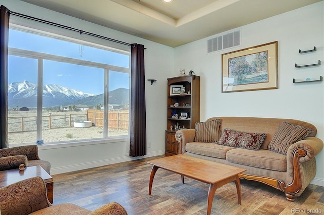 living area with a mountain view, visible vents, wood finished floors, and a healthy amount of sunlight