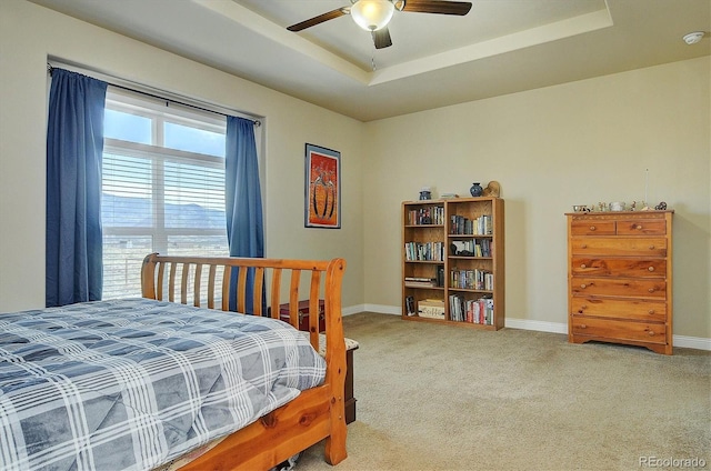 bedroom with carpet floors, baseboards, a raised ceiling, and a ceiling fan