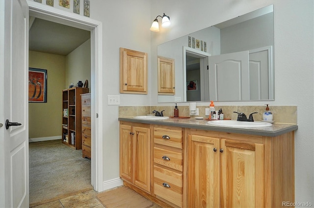 bathroom with double vanity, a sink, tile patterned flooring, and baseboards