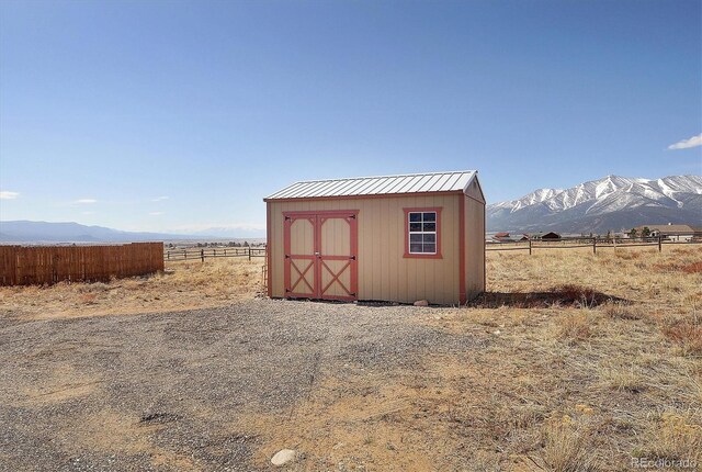 view of shed with a mountain view, fence, and a rural view