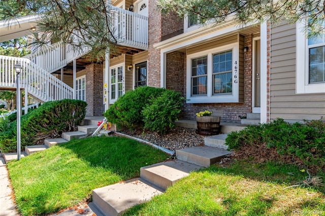 4676 S Dillon Ct Unit G, Aurora, CO 80015 - doorway to property with brick siding, a balcony, and a lawn
