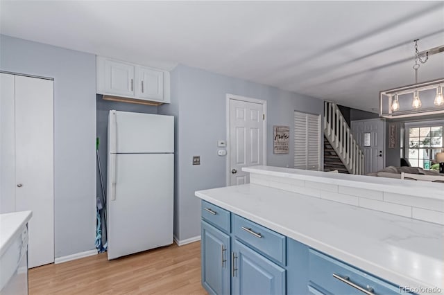 4676 S Dillon Ct Unit G, Aurora, CO 80015 - kitchen featuring freestanding refrigerator, blue cabinetry, light wood-style floors, light countertops, and open floor plan