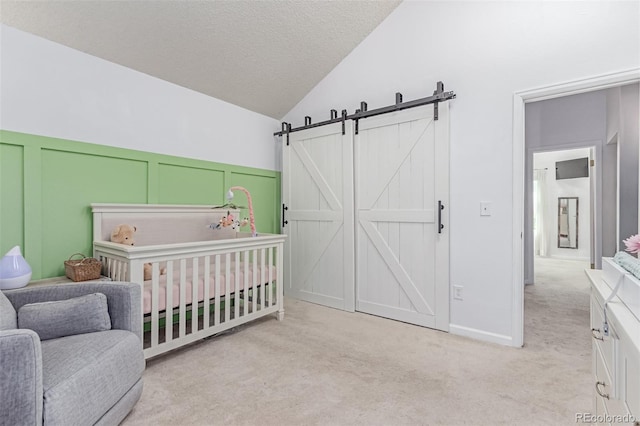 4676 S Dillon Ct Unit G, Aurora, CO 80015 - carpeted bedroom featuring vaulted ceiling, a nursery area, a decorative wall, a barn door, and a textured ceiling