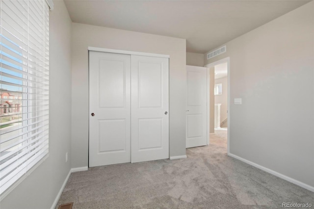 unfurnished bedroom with light carpet and a closet