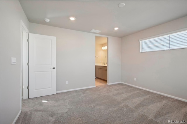 unfurnished bedroom featuring light carpet and connected bathroom