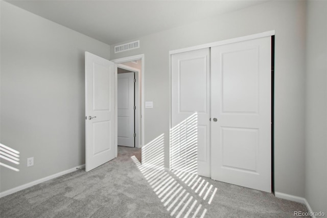 unfurnished bedroom with a closet and light colored carpet