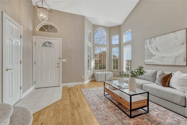 foyer entrance featuring an inviting chandelier, high vaulted ceiling, and light hardwood / wood-style flooring