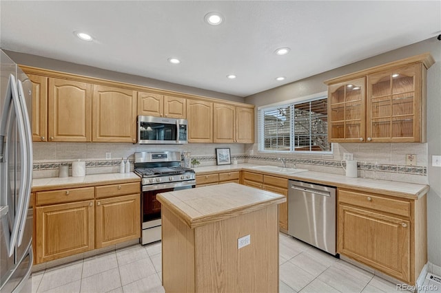 kitchen featuring a kitchen island, sink, decorative backsplash, light tile patterned floors, and stainless steel appliances