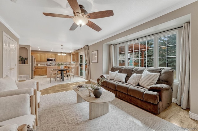 living room featuring ornamental molding, ceiling fan with notable chandelier, and light hardwood / wood-style flooring