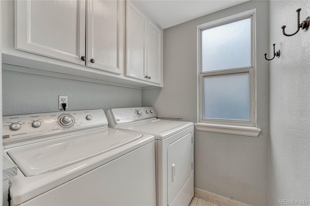 clothes washing area featuring washing machine and dryer and cabinets