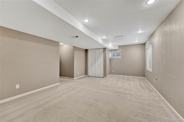 empty room with light colored carpet and a textured ceiling