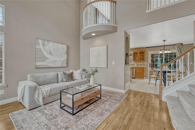 living room with a notable chandelier, a towering ceiling, and light hardwood / wood-style flooring