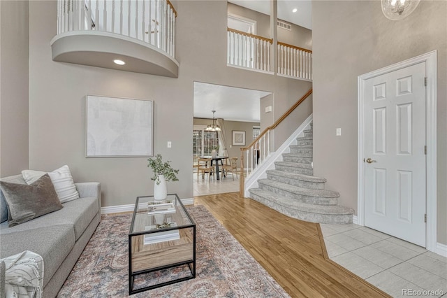 living room with a notable chandelier, light hardwood / wood-style floors, and a high ceiling