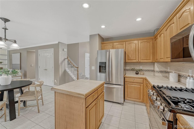 kitchen with tile countertops, a center island, decorative light fixtures, stainless steel appliances, and decorative backsplash