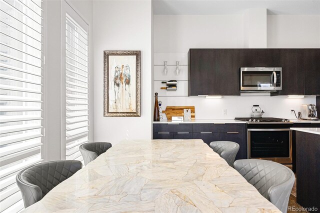 4395 Zuni St, Denver, CO 80211 - kitchen featuring appliances with stainless steel finishes, light countertops, modern cabinets, dark brown cabinets, and a breakfast bar