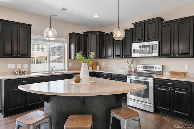 kitchen featuring pendant lighting, stainless steel appliances, dark wood-type flooring, and sink