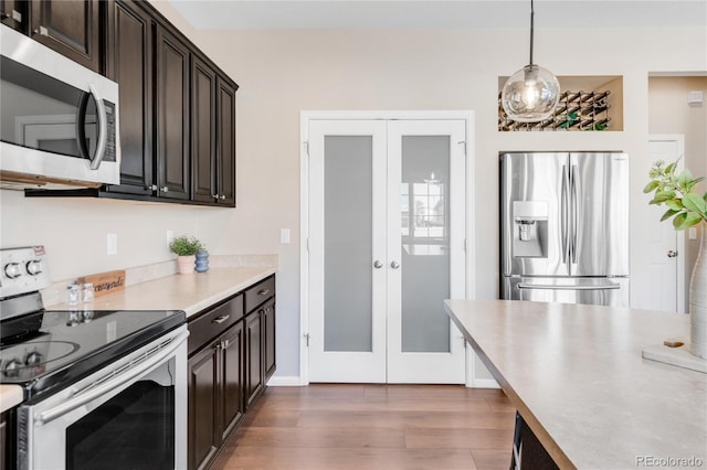 kitchen featuring appliances with stainless steel finishes, dark brown cabinetry, decorative light fixtures, and french doors