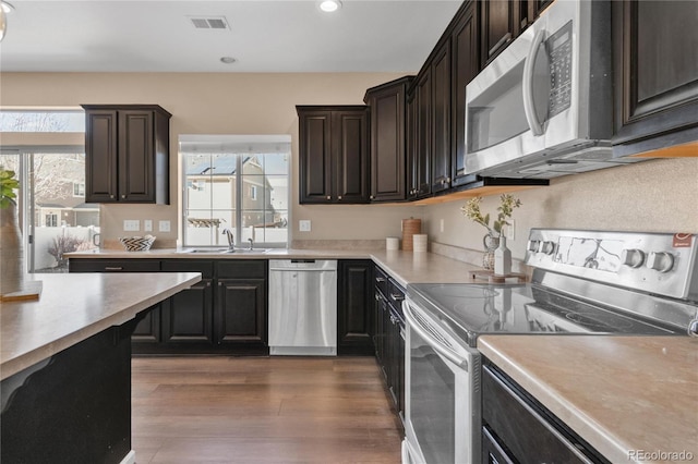 kitchen featuring sink, dark wood-type flooring, dark brown cabinets, and appliances with stainless steel finishes