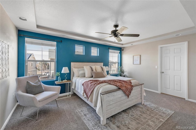 bedroom with ceiling fan, a raised ceiling, and carpet floors