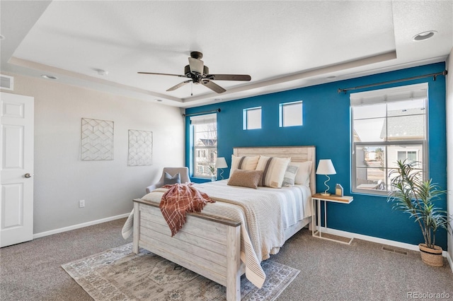 carpeted bedroom featuring a tray ceiling and ceiling fan