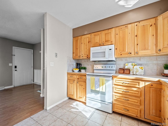 kitchen with light tile patterned flooring, light brown cabinets, backsplash, and white appliances