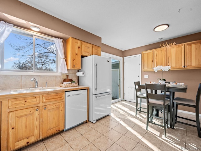 kitchen with tasteful backsplash, sink, white appliances, and light tile patterned floors