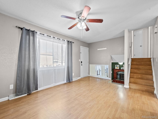 unfurnished living room featuring ceiling fan, a textured ceiling, and light wood-type flooring