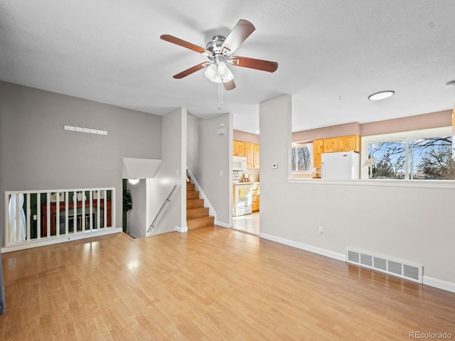 unfurnished living room featuring a textured ceiling, ceiling fan, and light wood-type flooring