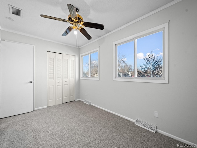 unfurnished bedroom featuring ornamental molding, carpet floors, a closet, and a textured ceiling