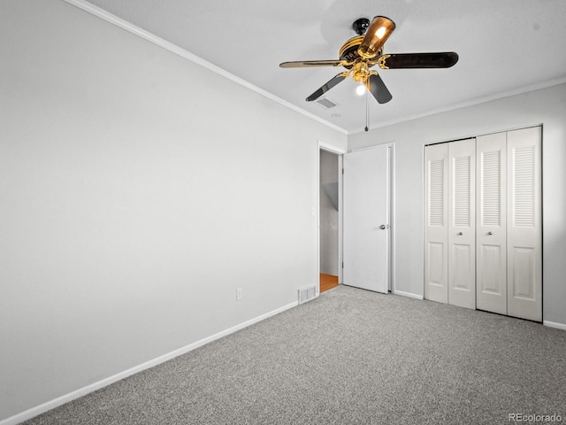 unfurnished bedroom featuring crown molding, ceiling fan, carpet floors, and a closet