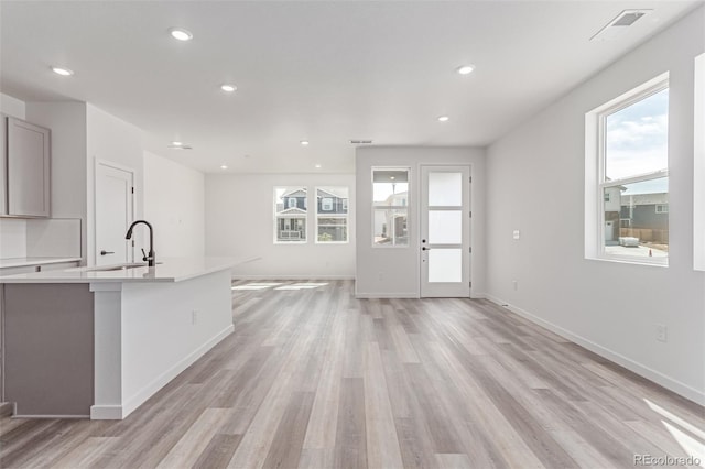 kitchen featuring a sink, plenty of natural light, open floor plan, light countertops, and recessed lighting