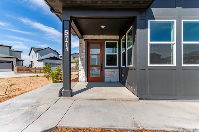 view of exterior entry with stone siding and fence