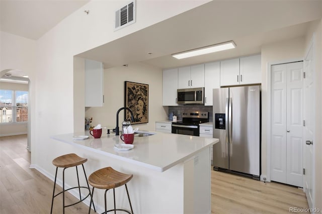 kitchen featuring white cabinetry, sink, stainless steel appliances, and kitchen peninsula