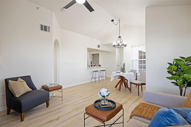 living room featuring ceiling fan with notable chandelier, high vaulted ceiling, and light hardwood / wood-style flooring