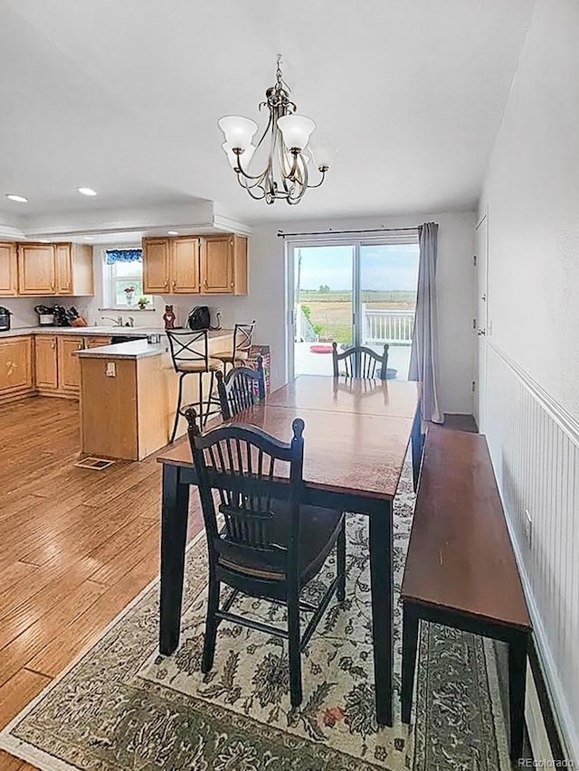 58117 E 42nd Dr, Strasburg, CO 80136 - dining space featuring light wood-style floors, plenty of natural light, a chandelier, recessed lighting, and a wainscoted wall